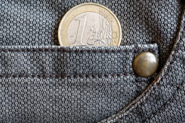 Euro coin with a denomination of one euro in the pocket of worn brown denim jeans