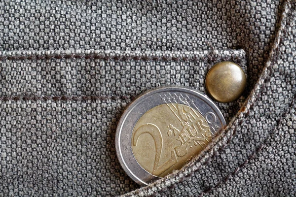 Euro coin with a denomination of 2 euro in the pocket of worn brown denim jeans