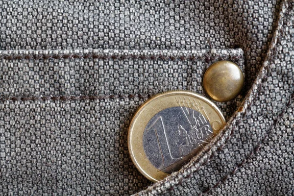 Moneta Euro con un taglio di 1 euro nella tasca dei jeans in denim marrone indossati — Foto Stock