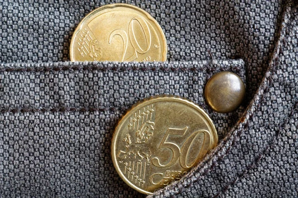 Moedas de euro com uma denominação de 20 e 50 cêntimos de euro no bolso de jeans de denim castanho desgastado — Fotografia de Stock