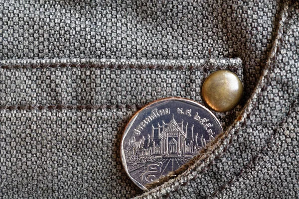 Thaise muntstuk met een nominale waarde van vijf baht in de zak van versleten bruin denim jeans — Stockfoto