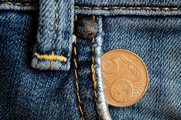 Euro coin with a denomination of 5 euro cents in the pocket of blue denim jeans