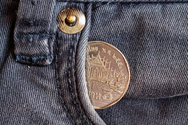 Moneta thailandese con un taglio di cinque baht nella tasca di jeans blu denim obsoleti — Foto Stock