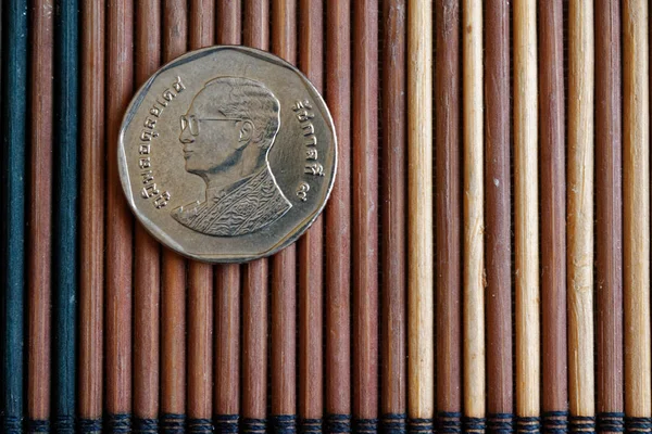 Тайские монеты номиналом 5 бат лежат на деревянном бамбуковом столе, хорошо для фона или открытки - задней стороне — стоковое фото