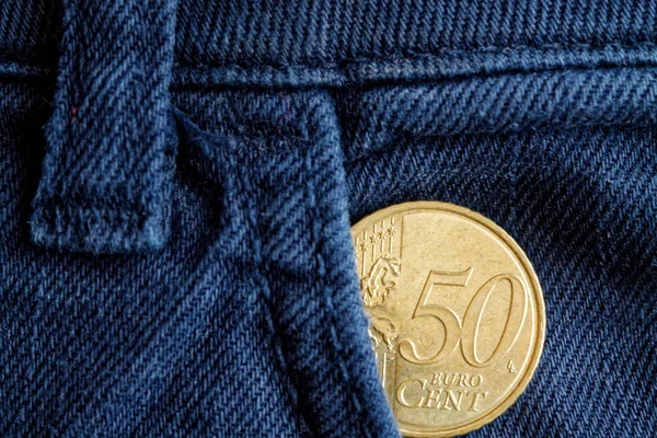 Euro coin with a denomination of 50 euro cents in the pocket of old blue denim jeans