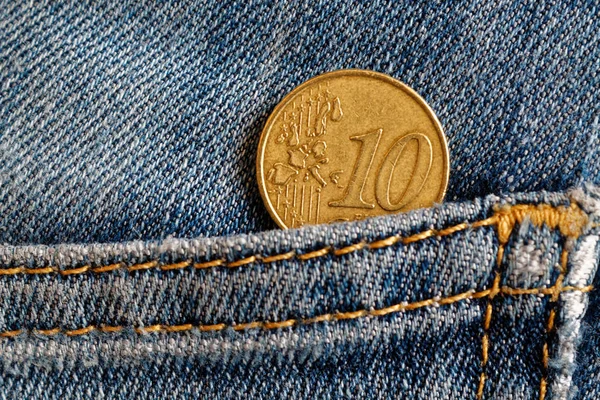 Euro coin with a denomination of 10 euro cents in the pocket of blue worn denim jeans