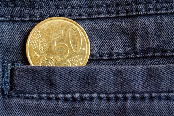 Euro coin with a denomination of 50 euro cents in the pocket of dark blue denim jeans