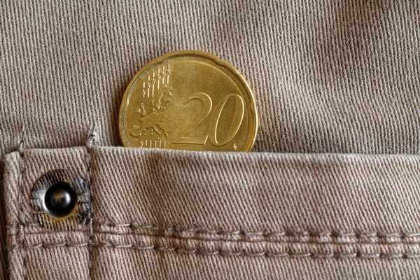 Euro coin with a denomination of 20 euro cents in the pocket of beige denim jeans