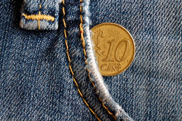 Euro coin with a denomination of 10 euro cents in the pocket of blue obsolete denim jeans
