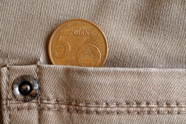 Euro coin with a denomination of 5 euro cents in the pocket of beige denim jeans