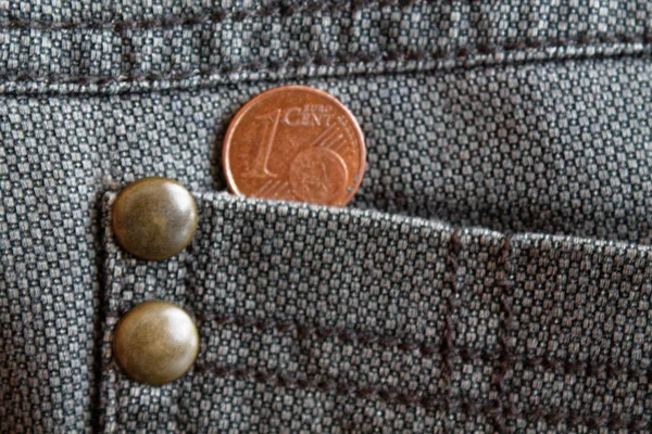 Euro coin with a denomination of one euro cent in the pocket of old worn brown denim jeans