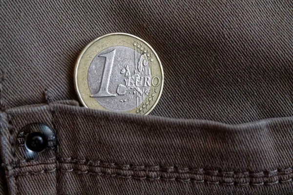 Euro coin with a denomination of 1 euro in the pocket of brown denim jeans