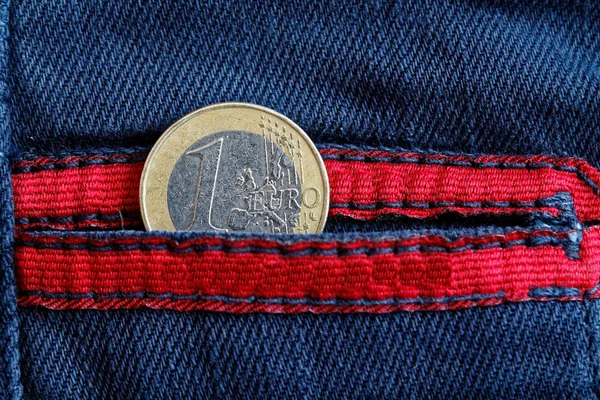 欧元硬币与一欧元面额的口袋里穿的蓝色牛仔牛仔裤与红色花边 — 图库照片