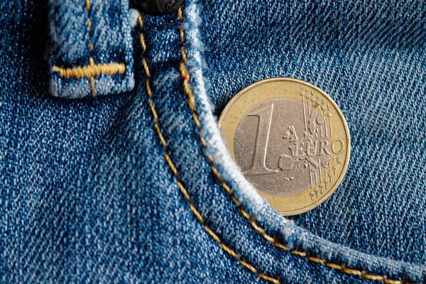 Euro coin with a denomination of 1 euro in the pocket of blue denim jeans
