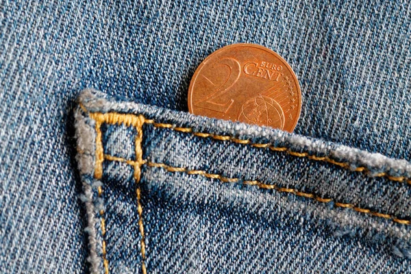 Euro coin with a denomination of 2 euro cent in the pocket of old blue denim jeans