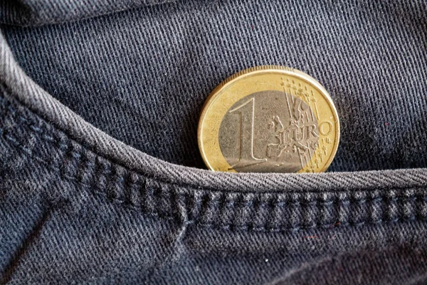 Euro coin with a denomination of one euro in the pocket of obsolete blue denim jeans