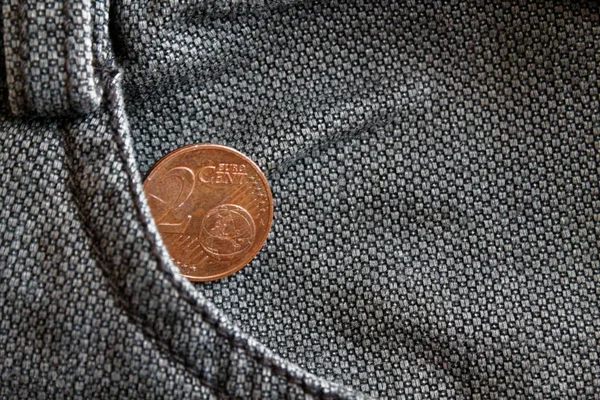 Euro coin with a denomination of two euro cent in the pocket of worn brown denim jeans