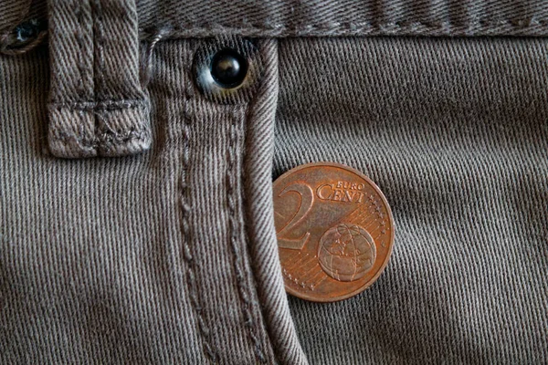 Монета евро номиналом в два евро в кармане старых джинсов в серых джинсах — стоковое фото