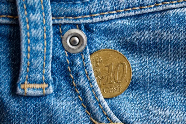 Euro coin with a denomination of ten euro cent in the pocket of vintage worn blue denim jeans