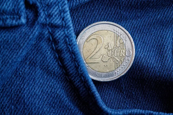 Moeda de euro com uma denominação de 2 euros no bolso de jeans jeans jeans antigos vintage azul — Fotografia de Stock