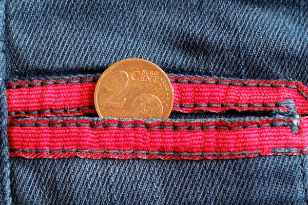 Moeda em euros com uma denominação de dois cêntimos de euro no bolso de jeans jeans azul desgastados, com atacadores vermelhos — Fotografia de Stock