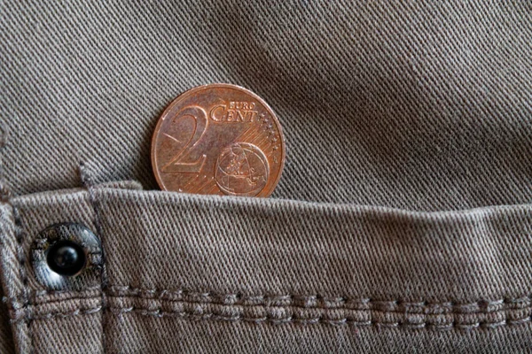 Euro coin with a denomination of 2 euro cent in the pocket of old gray denim jeans