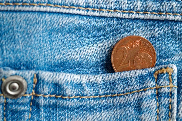 Euro coin with a denomination of 2 euro cent in the pocket of old worn blue denim jeans