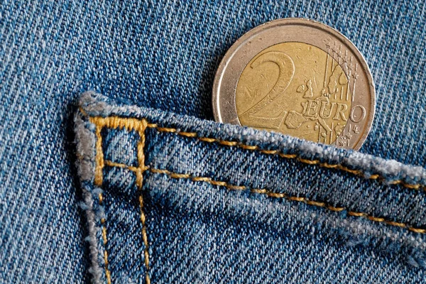 Moneta Euro con un taglio di due euro nella tasca di jeans blu denim vintage — Foto Stock