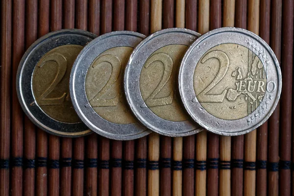 Τέσσερα ευρώ νομίσματα βρίσκονται σε ξύλινα μπαμπού πίνακα σε μια σειρά ονομαστική αξία είναι 2 ευρώ — Φωτογραφία Αρχείου