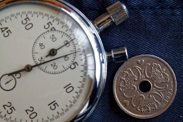 Dänemark-Münze mit einer Stückelung von zwei Kronen (Krone) (Rückseite) und Stoppuhr auf dunkelblauem Jeans-Hintergrund - geschäftlicher Hintergrund — Stockfoto