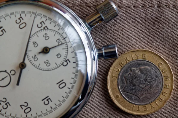 Türkische Münze mit einer Stückelung von einer Lira (Rückseite) und Stoppuhr auf abgenutztem beigen Jeanshintergrund - geschäftlicher Hintergrund — Stockfoto