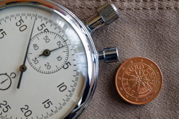 Euromunten met een nominale waarde van twee eurocent (achterkant) en stopwatch op oude beige jeans achtergrond - zakelijke achtergrond — Stockfoto