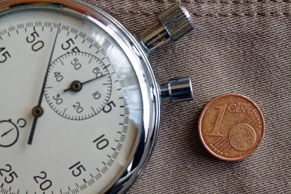 Euromünze im Wert von 1 Euro-Cent und Stoppuhr auf altem beigen Jeans-Hintergrund - geschäftlicher Hintergrund — Stockfoto