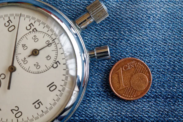 Pièce en euros avec une valeur unitaire de 1 centime d'euro et chronomètre sur fond de denim bleu usé - arrière-plan d'affaires — Photo