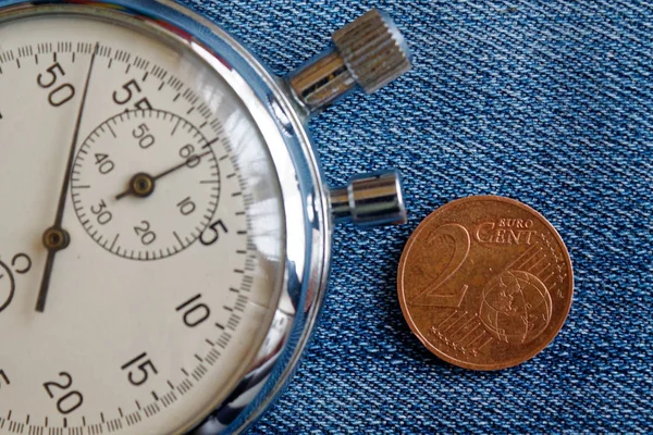 Pièce en euros avec une valeur unitaire de 2 centimes d'euro et chronomètre sur fond de denim bleu usé - fond d'affaires — Photo