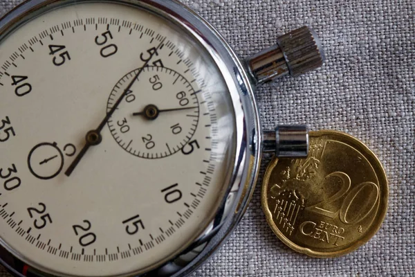 Euromunten met een nominale waarde van 20 eurocent en stopwatch op witte linnen achtergrond - zakelijke achtergrond — Stockfoto