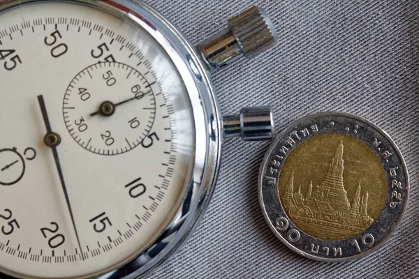 Thai coin with a denomination of 10 baht and stopwatch on gray denim backdrop - business background — Stock Photo, Image