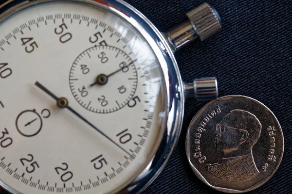 Thai coin with a denomination of five baht (back side) and stopwatch on black denim backdrop - business background — Stock Photo, Image