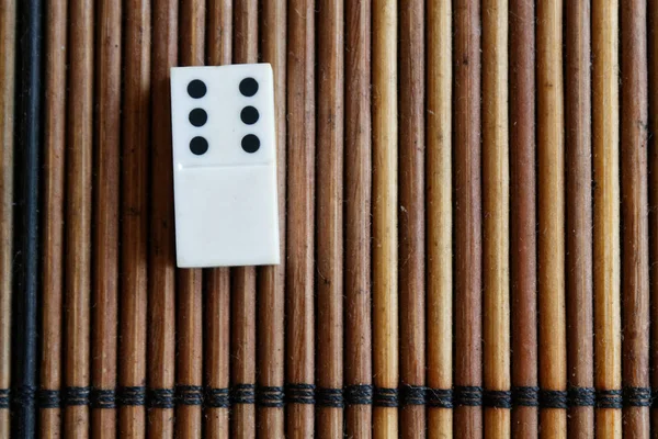 Kawałku Domino na tle brązowy drewniany stół bambusa. Domino pusta - 6 punktów. — Zdjęcie stockowe