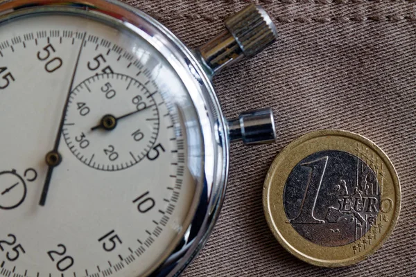 Pièce en euros avec une valeur unitaire de 1 euro et chronomètre sur fond vieux jean beige - fond d'entreprise — Photo