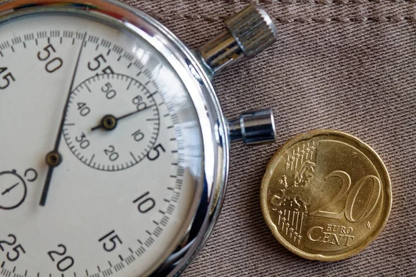 Euro coin with a denomination of 20 euro cents and stopwatch on old beige jeans backdrop - business background — Stock Photo, Image