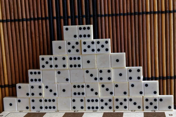 Pirâmide de peças de dominó sobre o fundo de mesa de madeira marrom de bambu — Fotografia de Stock
