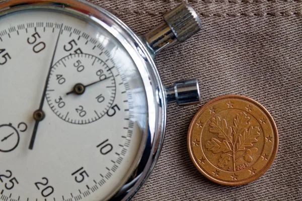 Euromunten met een nominale waarde van vijf euro cent (achterkant) en stopwatch op oude beige jeans achtergrond - zakelijke achtergrond — Stockfoto