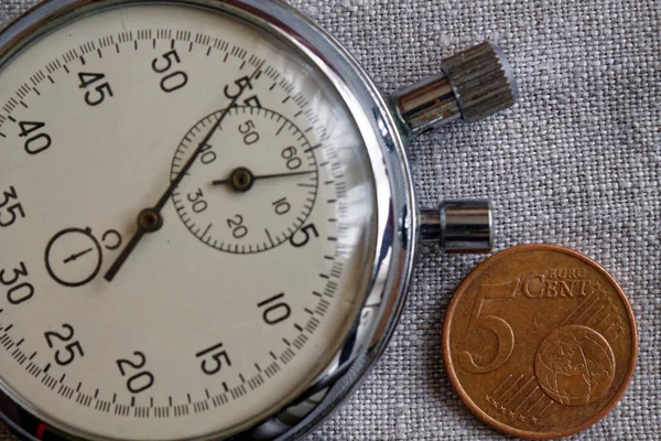 Euromunten met een nominale waarde van 5 eurocent en stopwatch op witte linnen achtergrond - zakelijke achtergrond — Stockfoto