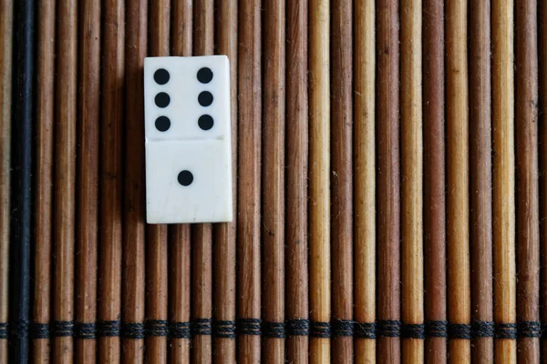 Kawałku Domino na tle brązowy drewniany stół bambusa. Domino set - jeden-6 punktów. — Zdjęcie stockowe