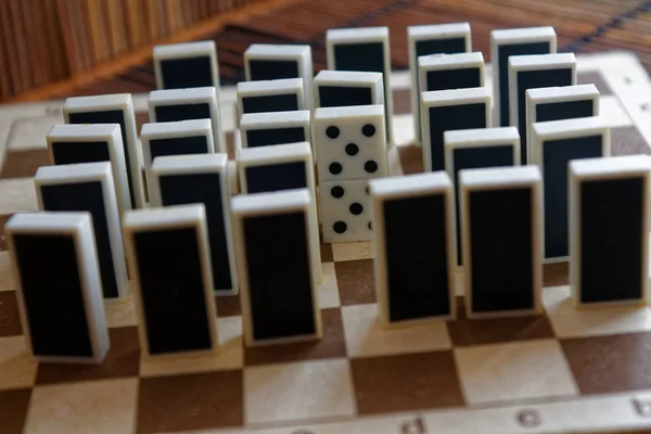 Dominosteine in einer Reihe und eine andere Statur, Rückseite, auf dem bambusbraunen Holztischhintergrund — Stockfoto