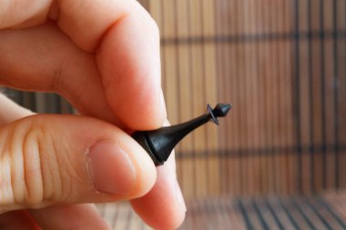Siyah plastik satranç şahı, adamın elinde, ahşap arka plan