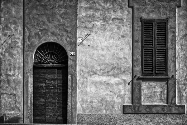 Fachada monocromática de antigua casa italia con ventanas persianas y puerta, fondo exterior —  Fotos de Stock