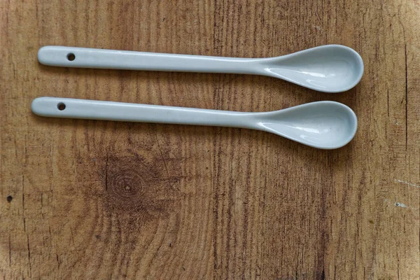 Colher de cerâmica branca na mesa de madeira, vista superior, fundo da cozinha — Fotografia de Stock