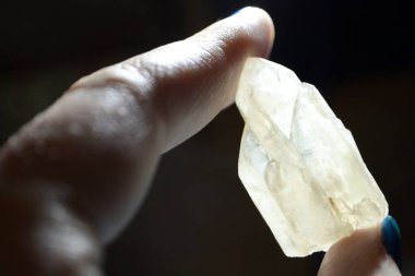 Koyu arkaplanda beyaz kaya kristal kuvarsı tutan eller